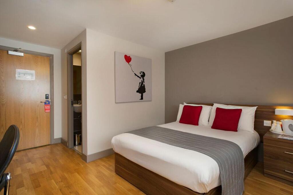 a bedroom with a large bed with red pillows at Britannia Study Hotel in Brighton & Hove