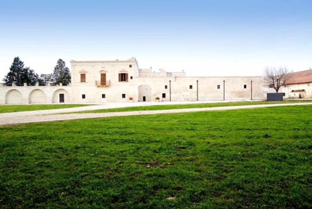 un grand bâtiment avec une pelouse devant lui dans l'établissement Masseria Rosario, à Grottaglie
