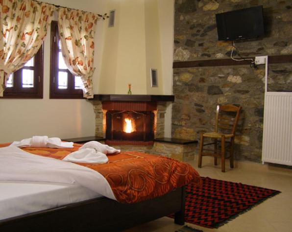 a bedroom with a large bed and a fireplace at Guesthouse Naouma in Panayítsa