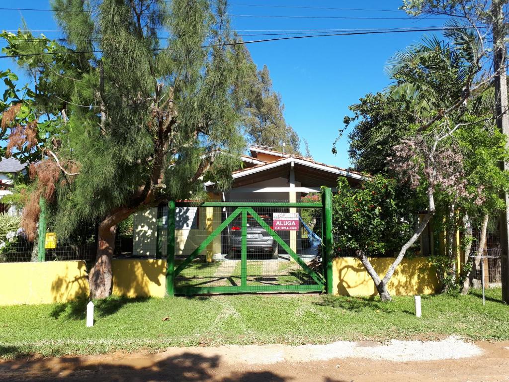 un cancello verde di fronte a una casa con un albero di Casa Praia da Barra, Garopaba a Garopaba