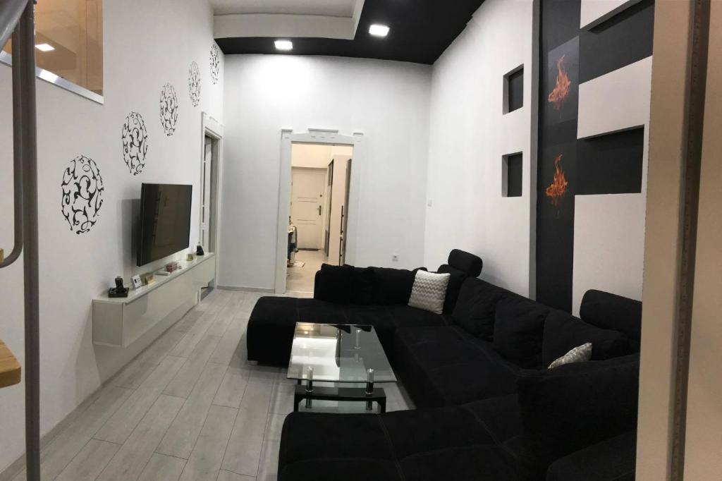 a living room with a black couch and a tv at Manyi Apartman in Debrecen