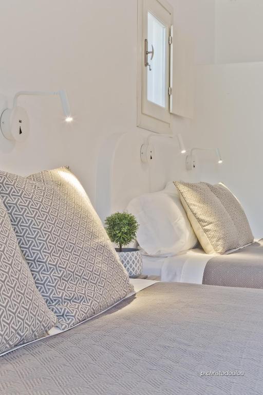 a white bedroom with two beds and a mirror at Lux View Villas in Kyra Panagia