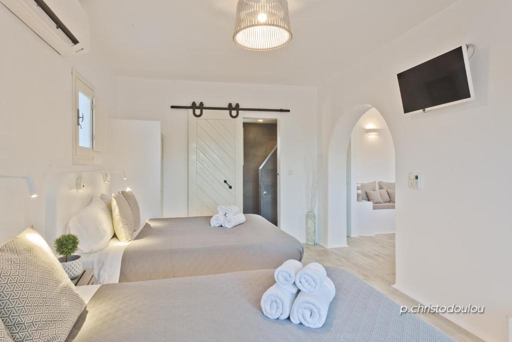 a white bedroom with two beds and a tv at Lux View Villas in Kyra Panagia