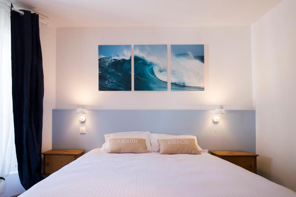 a bedroom with a bed with two paintings on the wall at BREVOCEAN Chb calme Côte Atlantique in Saint-Brévin-lʼOcéan