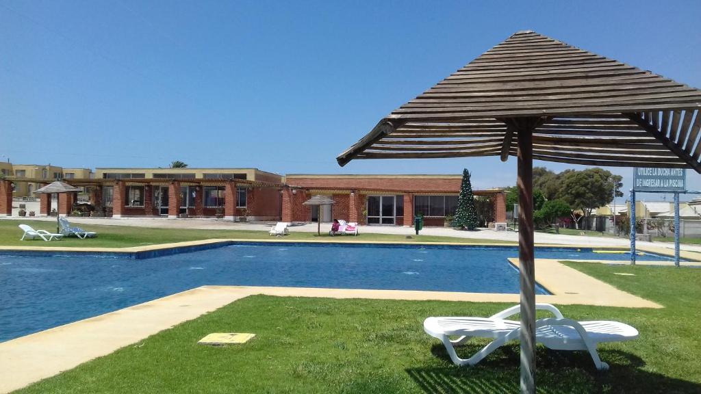 una sombrilla de patio, 2 sillas y una piscina en Casa Bahia Inglesa, en Bahía Inglesa