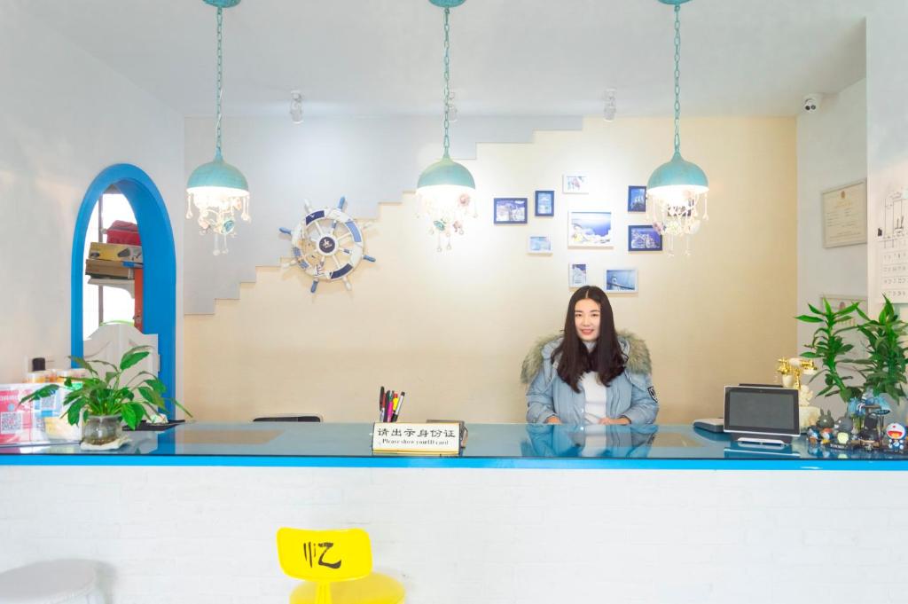 a woman sitting at a counter in an office at Qiannuo Youth Hostel in Hangzhou