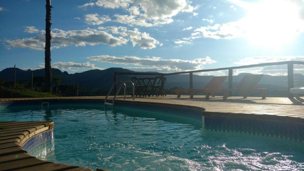 a swimming pool with a playground and mountains in the background at Pousada Trinca Ferro in Bom Retiro