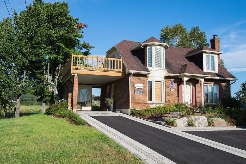 a brick house with a balcony on a driveway at 271 - La Victorienne - Les Immeubles Charlevoix in Baie-Saint-Paul