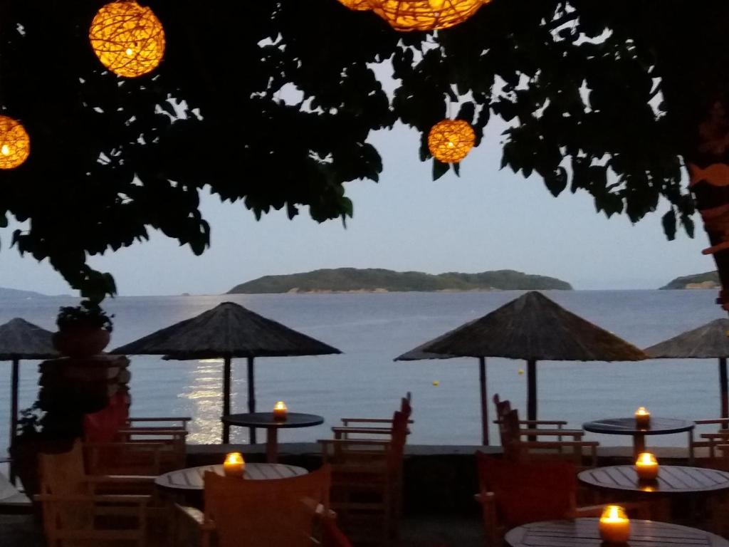 a view of the water from a restaurant with tables and umbrellas at Maniatis Garden in Achladies
