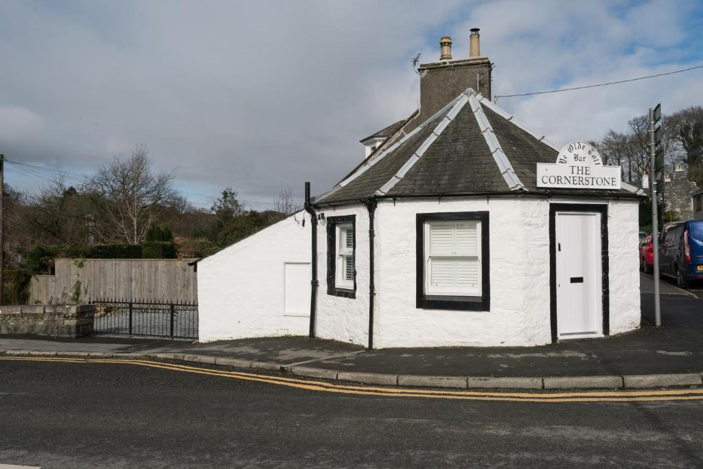 een klein wit gebouw op de hoek van een straat bij The Toll House in Newton Stewart