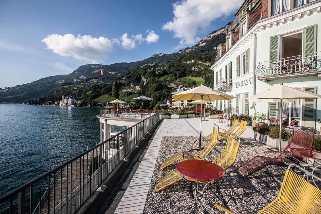 a balcony with chairs and tables next to the water at Hotel Terrasse am See in Vitznau