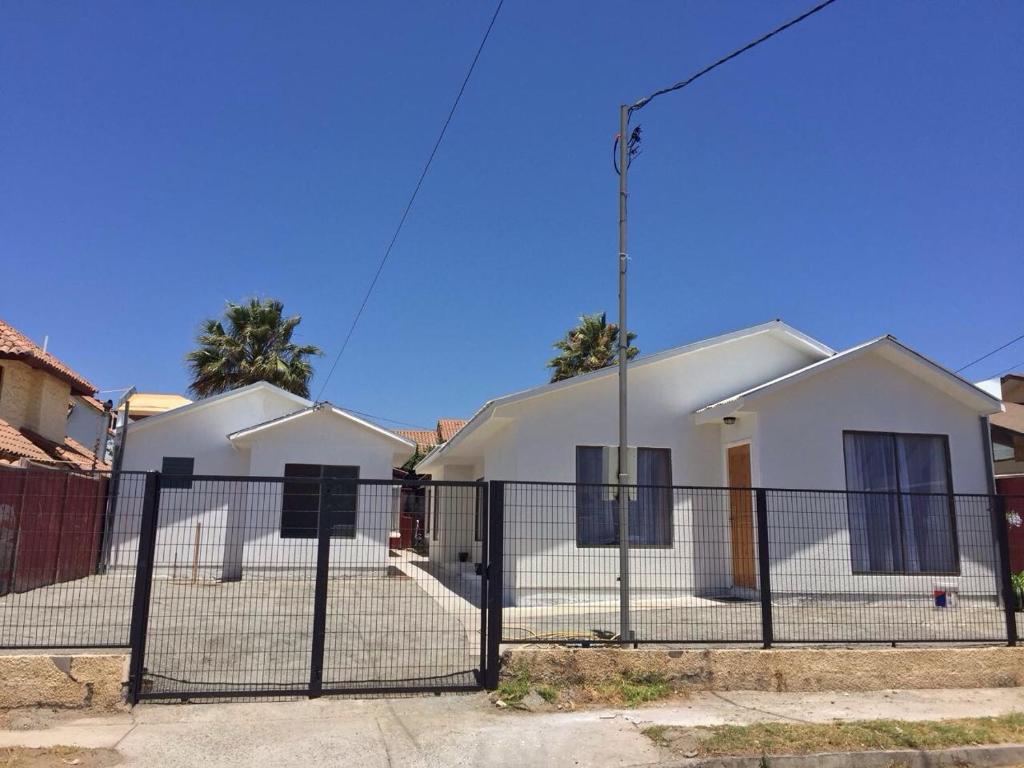 una cerca frente a una casa blanca en Cabañas Herradura Oriente, en Coquimbo