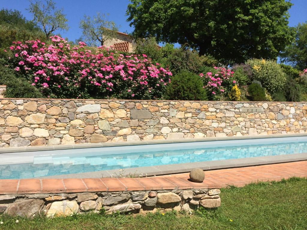 een stenen muur met een zwembad en bloemen bij La Casa Toscane in Capannori