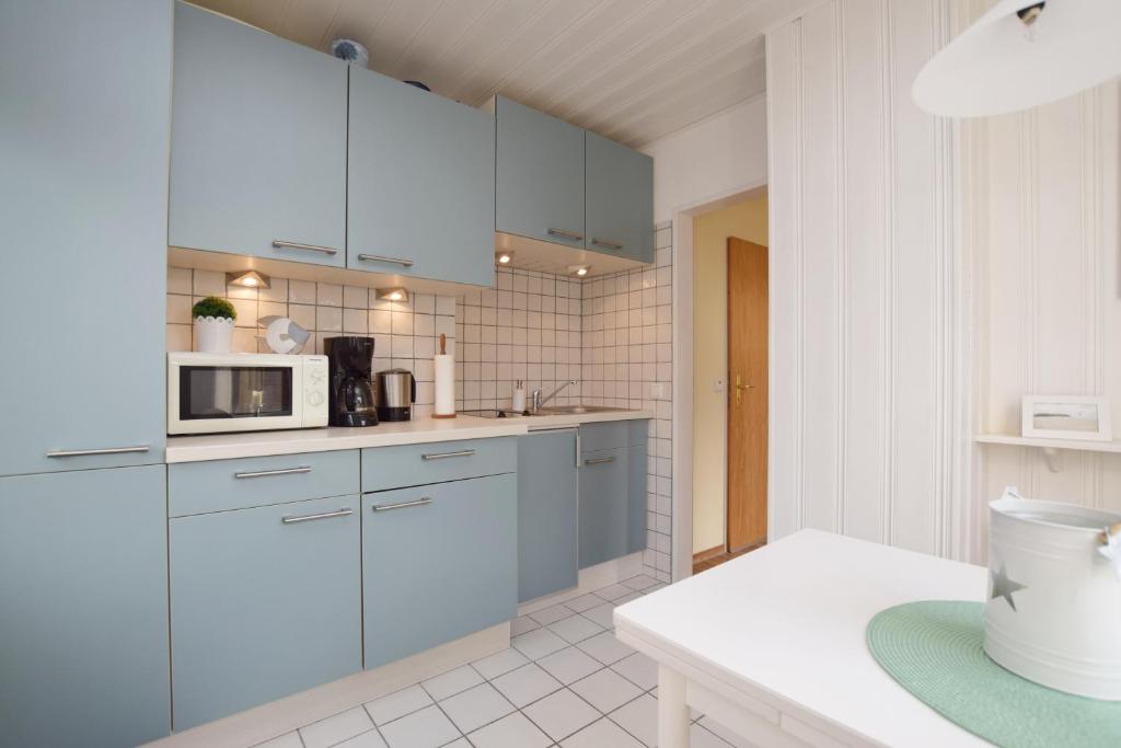 a kitchen with blue cabinets and a microwave at Apartment Ostseebleibe in Glücksburg