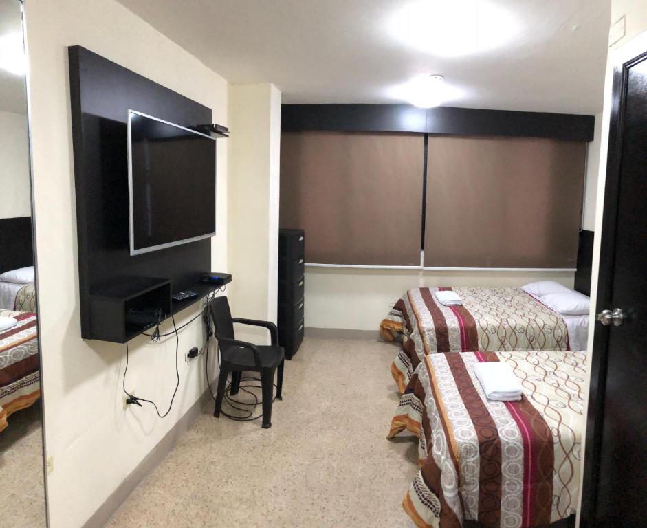 um quarto de hotel com duas camas e uma televisão de ecrã plano em residencia terreros ideal 4 personas em Guayaquil