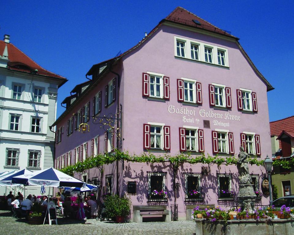 a pink building with people sitting in front of it at Gasthof & Hotel Goldene Krone in Iphofen