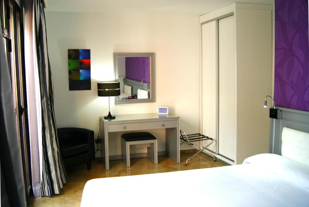 a bedroom with a desk with a lamp and a chair at Hotel Molinos in Granada