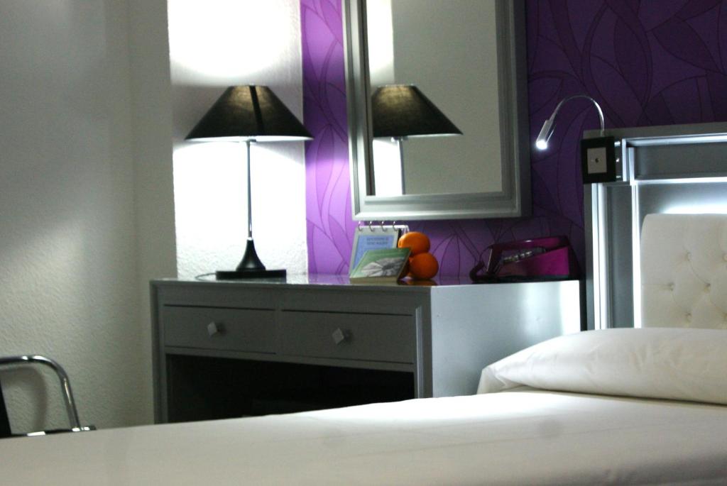 1 dormitorio con mesa, 2 lámparas y espejo en Hotel Molinos, en Granada