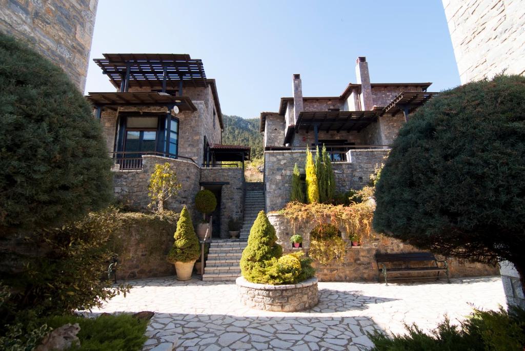 an old stone building with trees and a bench at Ostra Menalon Luxury Suites in Kardharás
