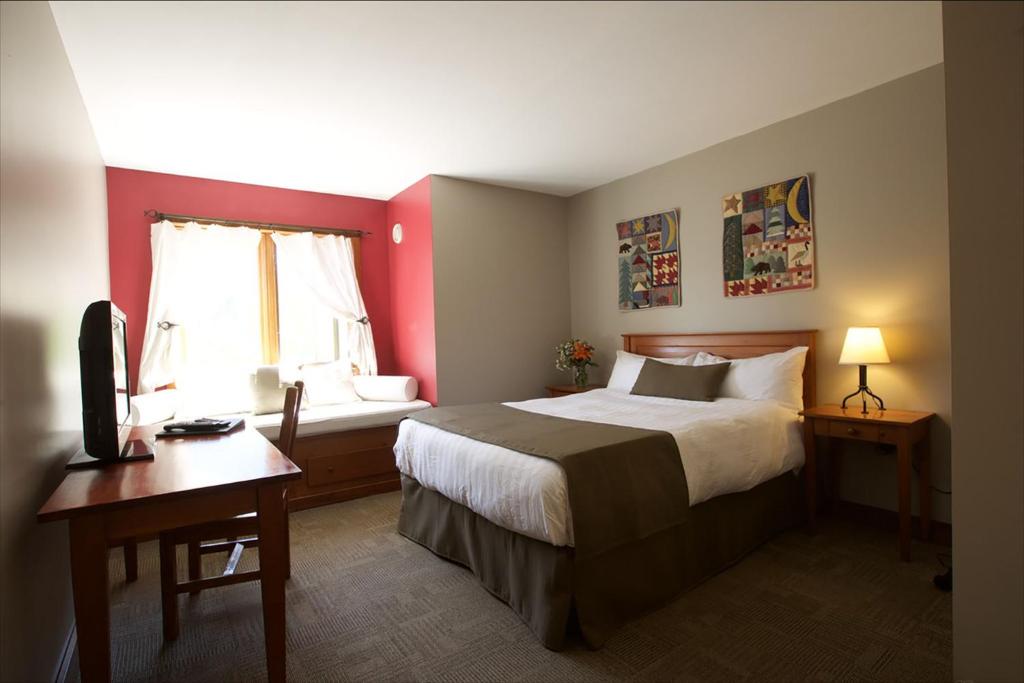 a bedroom with a bed and a desk and a window at Howe Sound Inn & Brewing Company in Squamish