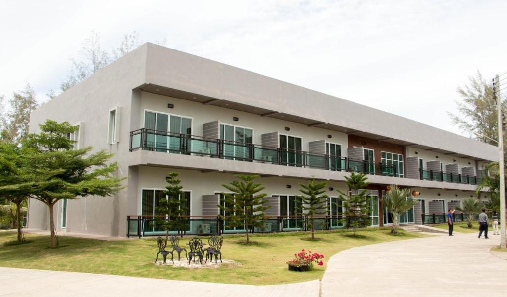een gebouw met tafels en stoelen ervoor bij Hadthong Resort in Pak Phayun