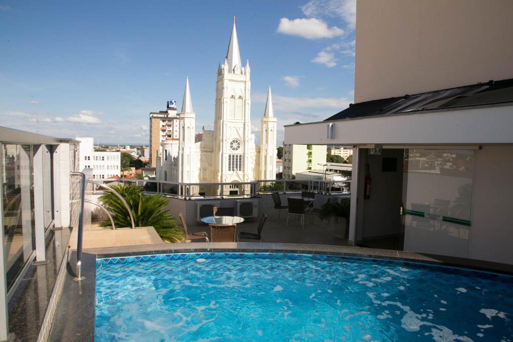 ein Pool auf dem Dach eines Gebäudes mit einer Kirche in der Unterkunft Executivo Hotel in Montes Claros