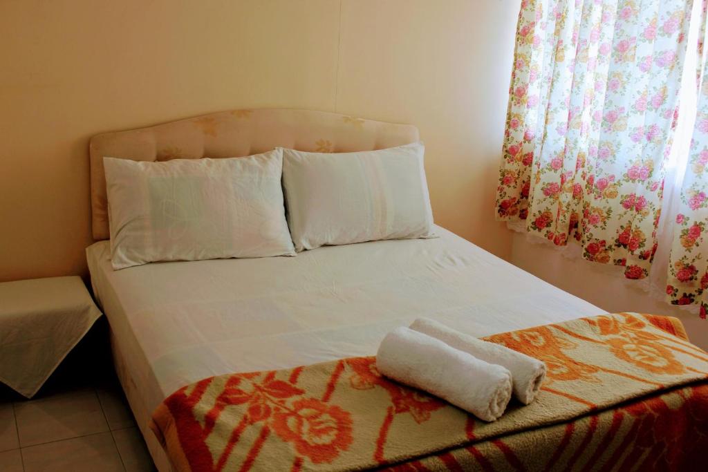 a bed with two towels sitting on top of it at Bayan Homestay in Bayan Lepas