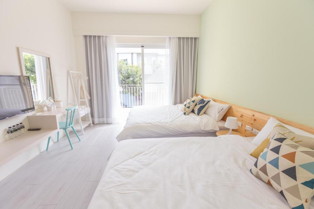 a white bedroom with two beds and a television at Let's Go Papa in Taitung City