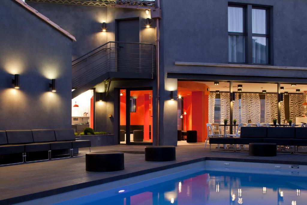 a house with a swimming pool in front of a house at Hôtel De L'octroi in Carcassonne