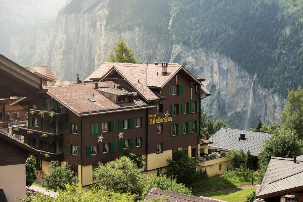 a building with green windows and a mountain at Hotel Edelweiss in Wengen