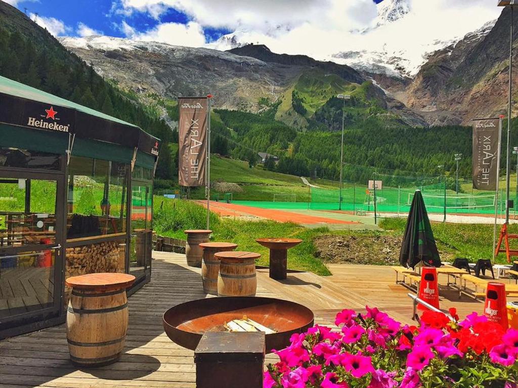 a restaurant with tables and flowers on a tennis court at Hotel THE LARIX ski-in ski-out in Saas-Fee