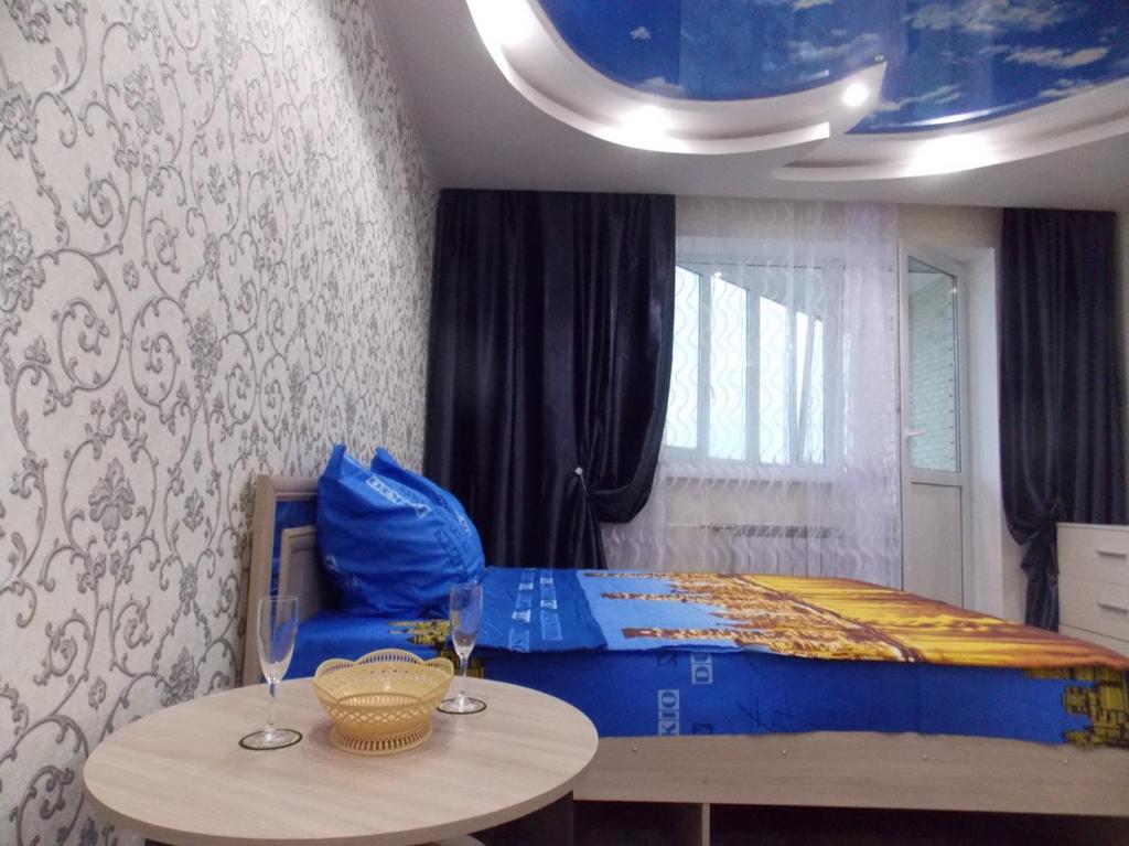 Gor'kogoにあるApartaments LUX STATUS Moskovsky Prospektのベッドルーム1室(青いベッド1台、ワイングラス付きのテーブル付)