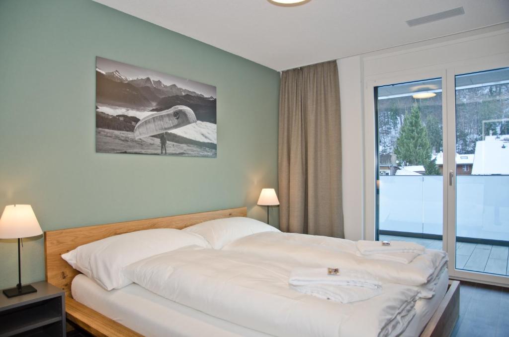 a bedroom with a large white bed with a window at Apartment Alperose - GriwaRent AG in Interlaken