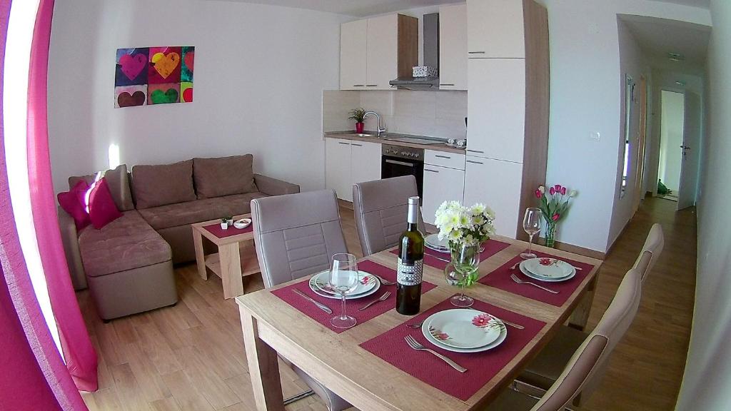 a living room with a dining room table and a kitchen at Apartments Tea in Podaca