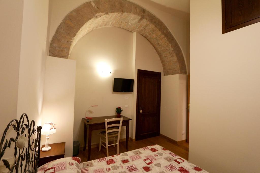sypialnia z łukiem, stołem i łóżkiem w obiekcie La Casina Colorata w Asyżu