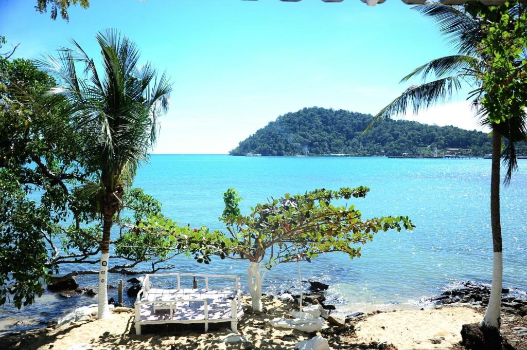 una playa con palmeras y vistas al océano en Secret Garden Family House, en Ko Chang