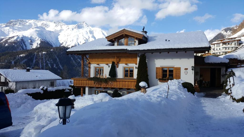 une maison recouverte de neige avec des montagnes en arrière-plan dans l'établissement Haus Brigitte, à Nauders