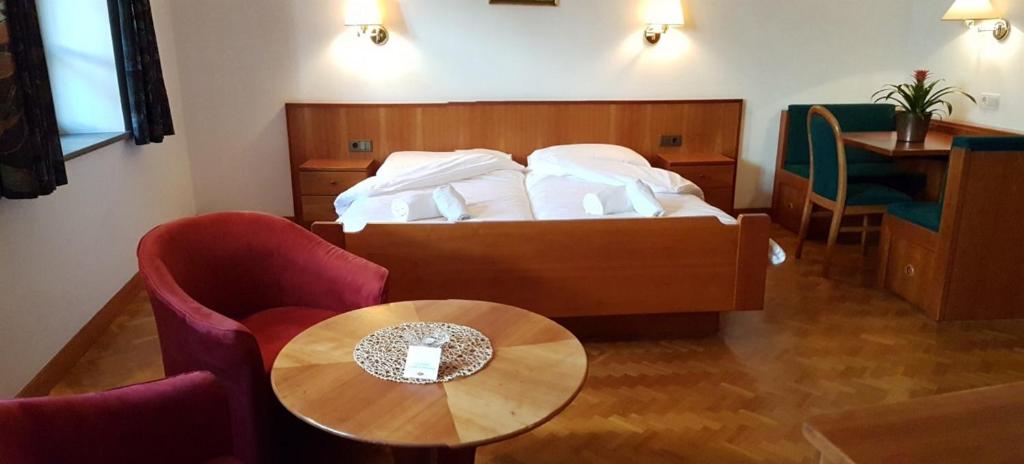 a bedroom with a bed and a table and chairs at Weißes Rössl in Appiano sulla Strada del Vino