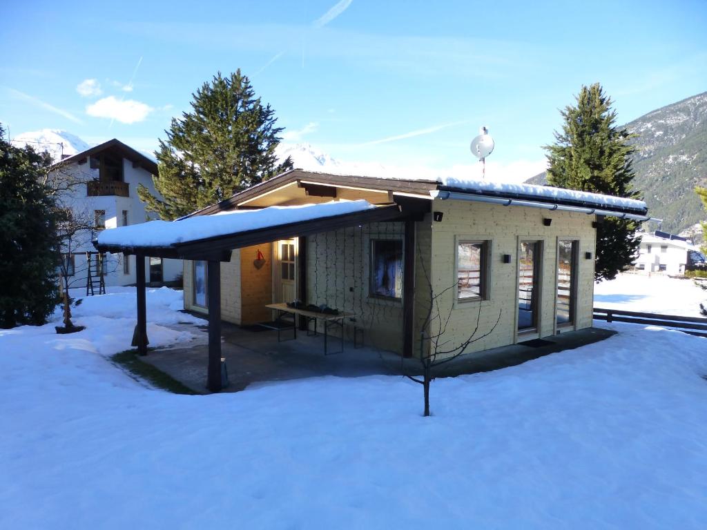 a small house with a snow covered roof in the snow at Chalet Auszeit in Arzl im Pitztal