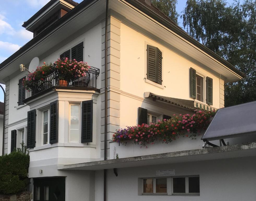 a white house with flowers on a balcony at B&B Stirnimann in Bunzen