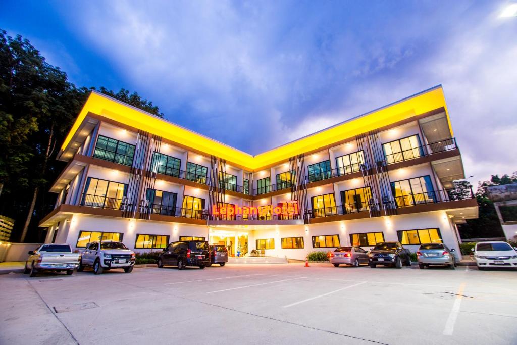 a large building with cars parked in a parking lot at The Lephant Hotel in Surat Thani