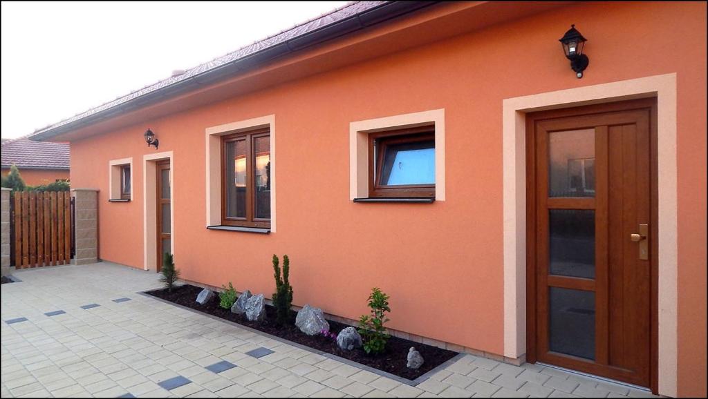 una casa naranja con una puerta y algunas plantas en Apartmány Andrea, en Břeclav