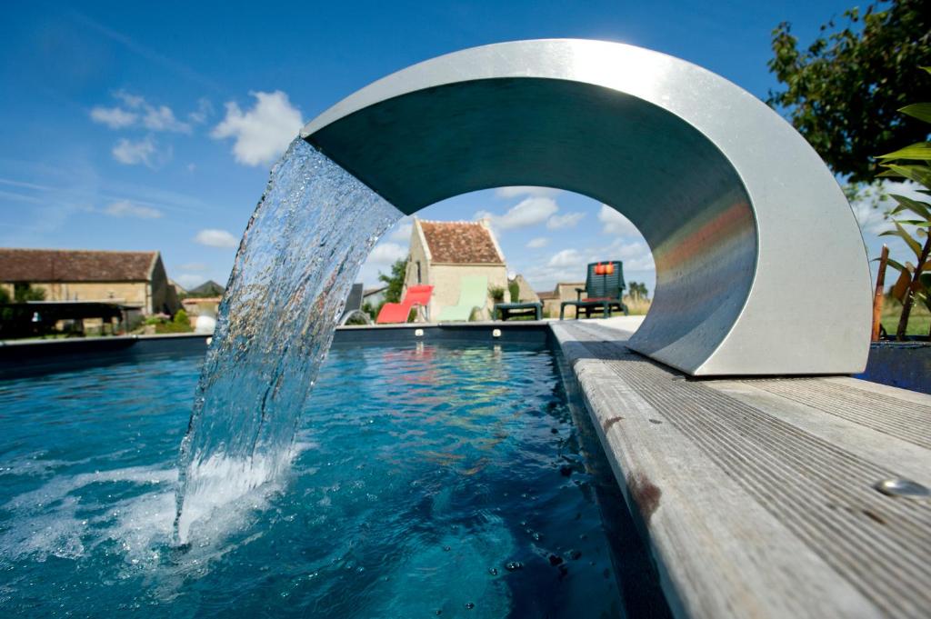 a pool with a water fountain in the middle at Le Domaine du Douet du Houle, Piscine & SPA, 2-19p in Courcy