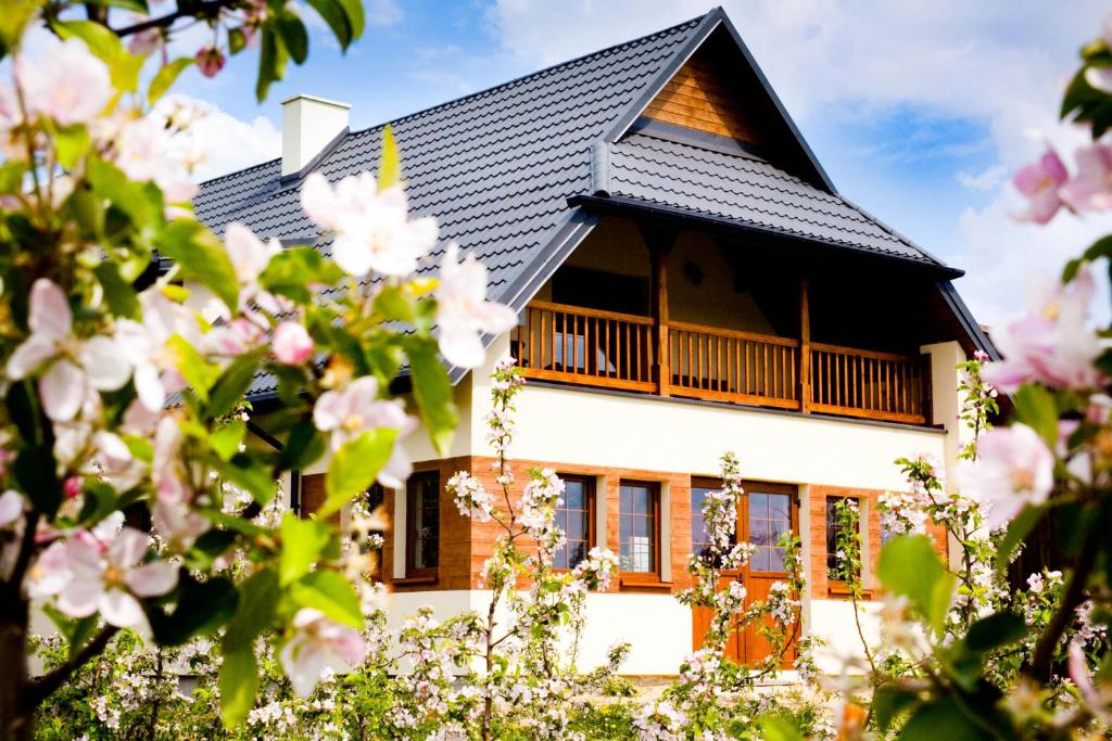 a house with a black roof and pink flowers at Agroturystyka Pod Jabłonią in Kazimierz Dolny