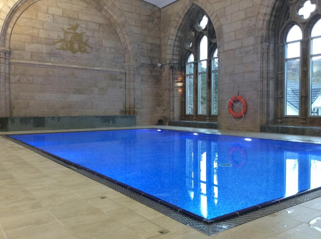 a large swimming pool with blue water in a building at Noble Apartment - Highland Club in Fort Augustus