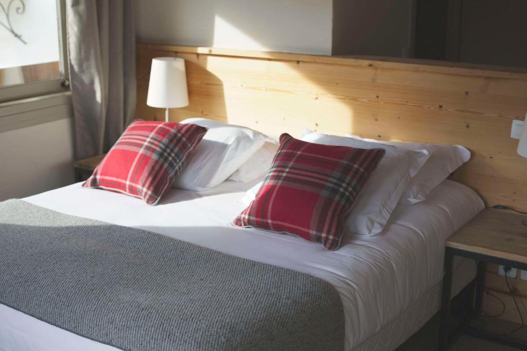 a bed with two red and white pillows on it at Hôtel Val d'Este in Saint-Gervais-les-Bains