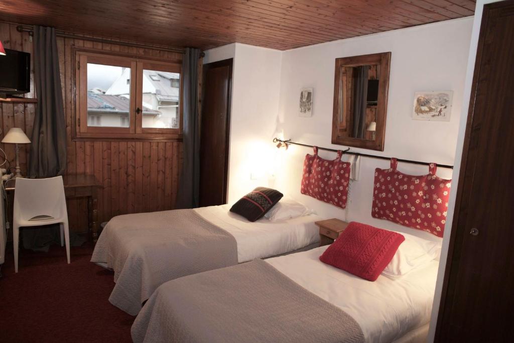 a hotel room with two beds and a table and a window at Hôtel Val d'Este in Saint-Gervais-les-Bains