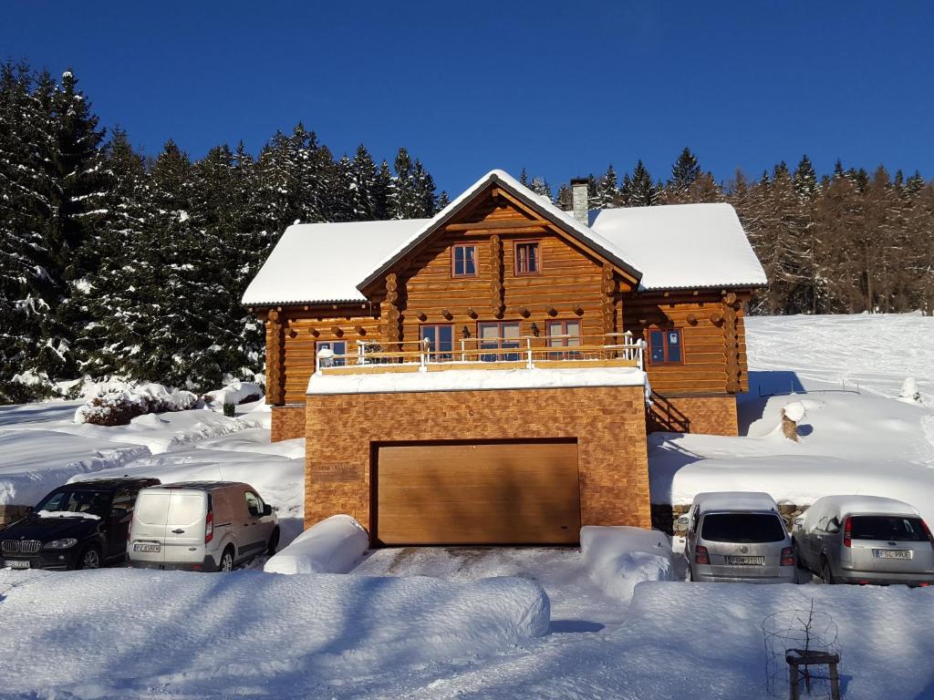 domek na śniegu z zaparkowanymi samochodami w obiekcie Chata - Srub Kašparáci w Jańskich Łaźniach