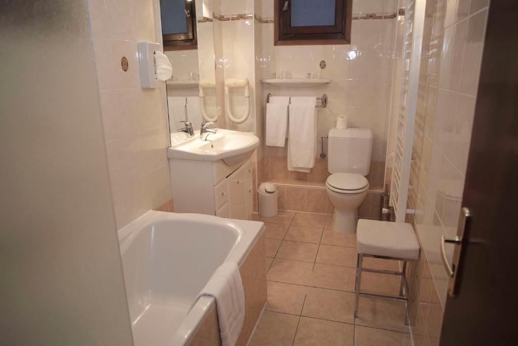 a bathroom with a tub and a toilet and a sink at Hôtel Val d'Este in Saint-Gervais-les-Bains