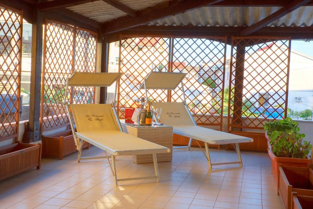 2 chaises assises sur une terrasse couverte avec fenêtres dans l'établissement Casa vacanze Gigli, à Numana